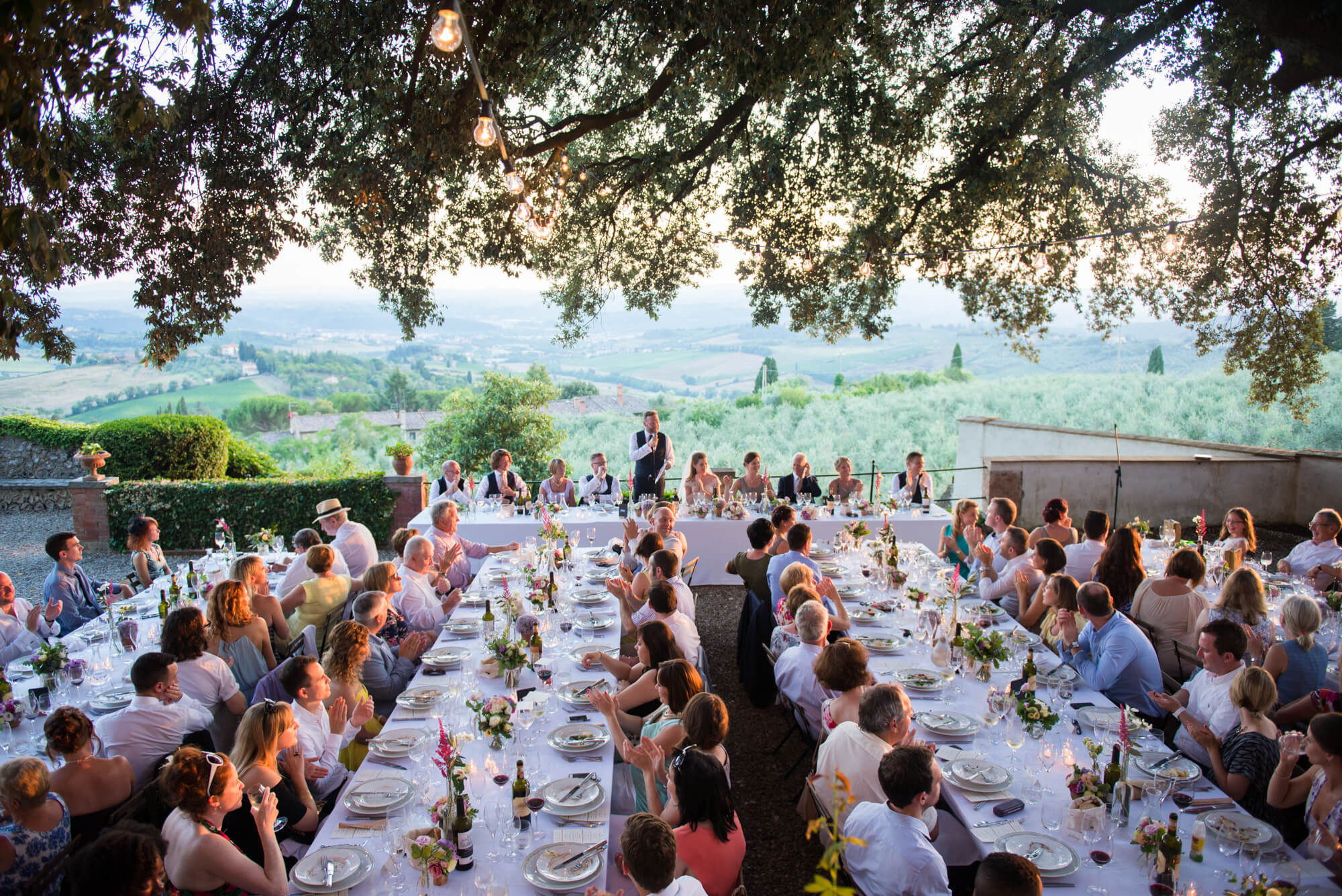 wedding breakfast under an oak tree in tuscany with festoon lighting